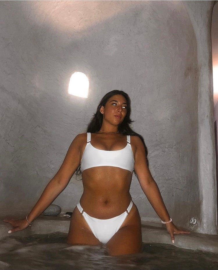 girl wearing white ribbed bikini scoop neck top with two silver round rings on each strap in the front. Adjustable straps.