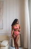 girl wearing a tube cut style coral / pink bikini top with high rise bottoms.